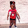 Kalani is registered to the contest to win money with this photo: birthday_badge, black_shoes, casual_clothing, child, concrete_wall, cute_hairstyle, daytime, girl, hair_bow, minnie_mouse, money, outdoor, person, pointing, red_shirt, shadow, shorts, sidewalk, standing, sunlight