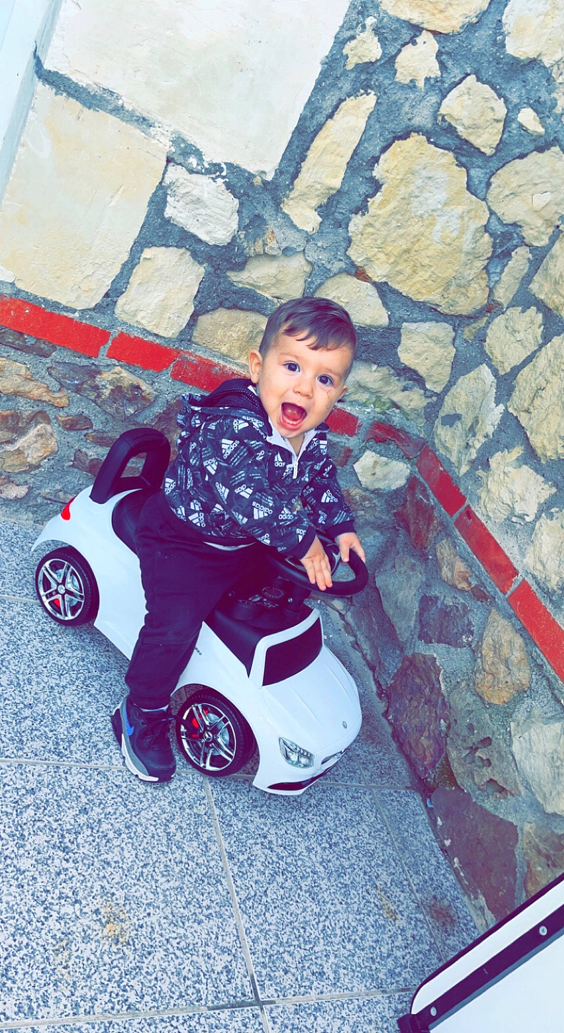 Aylan participe au concours pour gagner de l'argent avec cette photo : automotive_design, automotive_wheel_system, baby, baby_products, baby_toddler_clothing, child, electric_blue, fun, happy, magenta, motor_vehicle, person, recreation, riding_toy, rolling, sitting, surprise, tire, toddler, travel