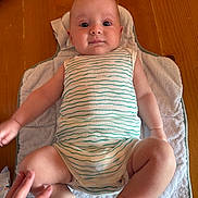 Léandre a rejoint le concours — aidez-le/la à gagner de superbes lots ! baby, infant, towel, wooden_table, striped_clothing, onesie, hand, skin, legs, arm, face, eyes, naked_feet, indoor, person, cute, child, human, soft_texture, comfort