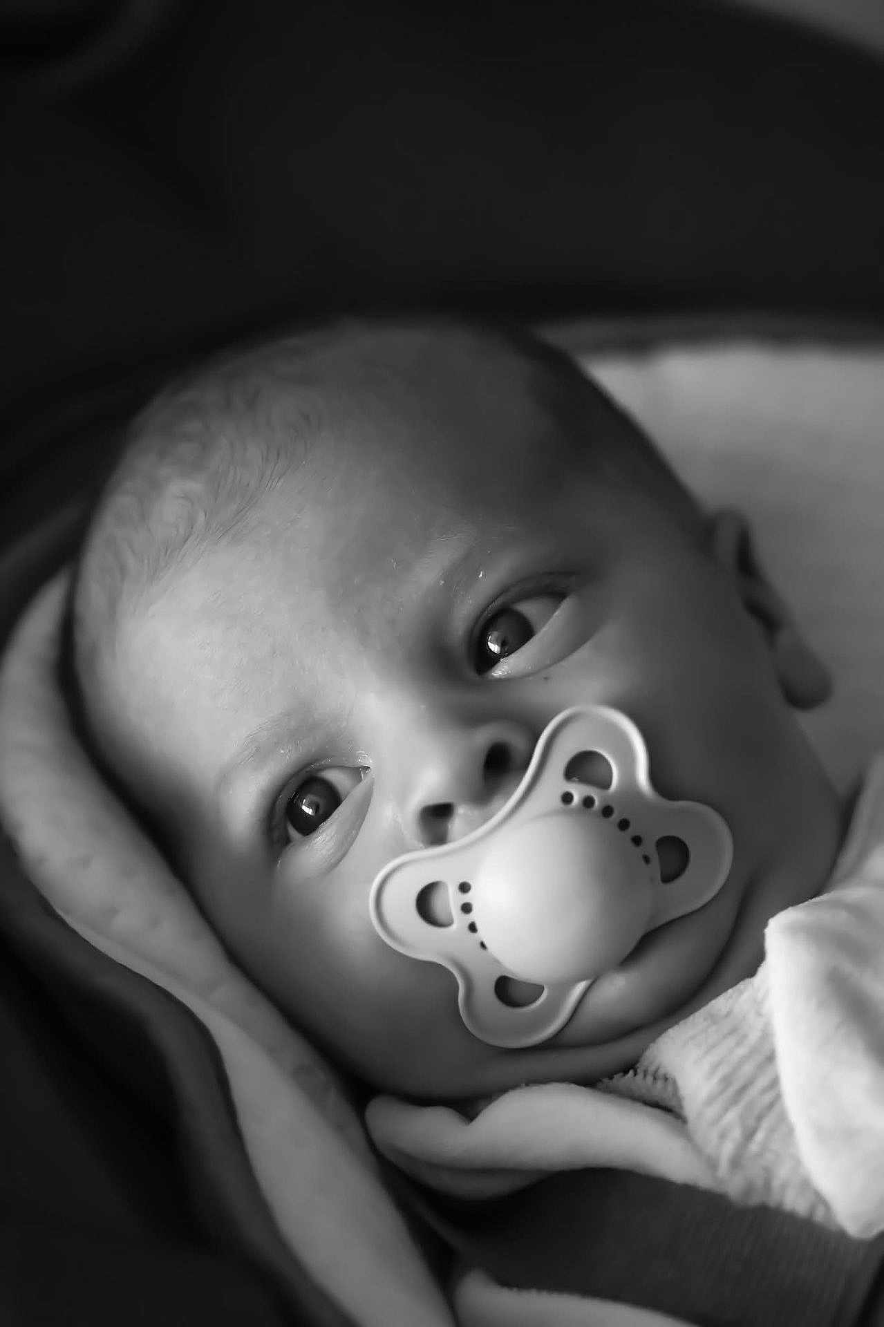 James participe au concours pour gagner de l'argent avec cette photo : baby, pacifier, close_up, black_and_white, blanket, infant, face, eyes, newborn, child, portrait, soft, cute, sleepwear, head, warm, cozy, young, expression, peaceful