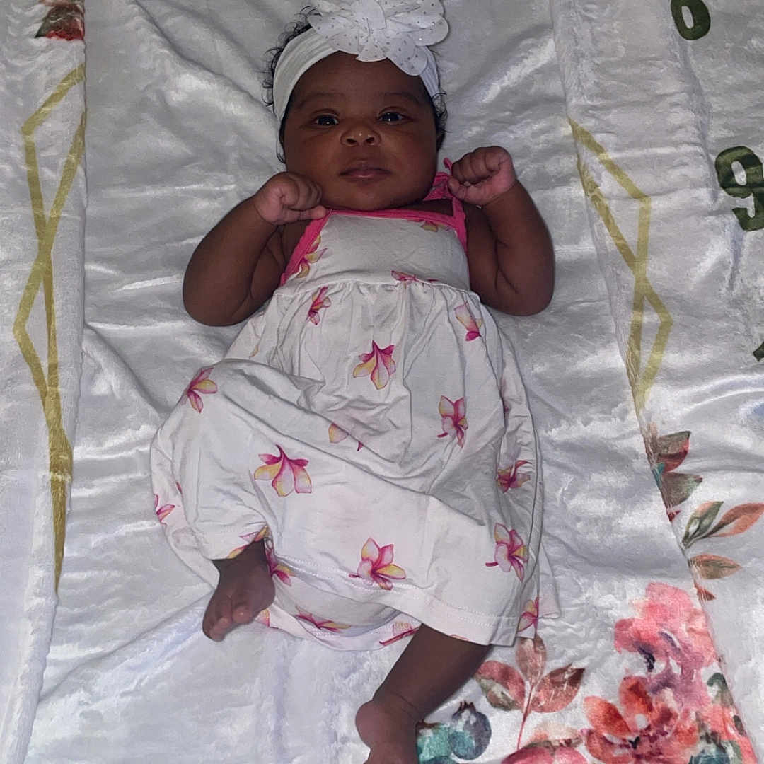 Kamali joined the competition — help win amazing prizes! baby, bed, blanket, bodypart, bonnet, clothing, crib, dress, face, finger, furniture, hand, hat, head, infantbed, newborn, person, photography, portrait, quilt