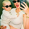 baby, child, woman, person, sunglasses, selfie, mirror, smartphone, fashion, casual_clothing, jewelry, bracelet, necklace, indoor, portrait, holding, cute, happy, modern, accessories