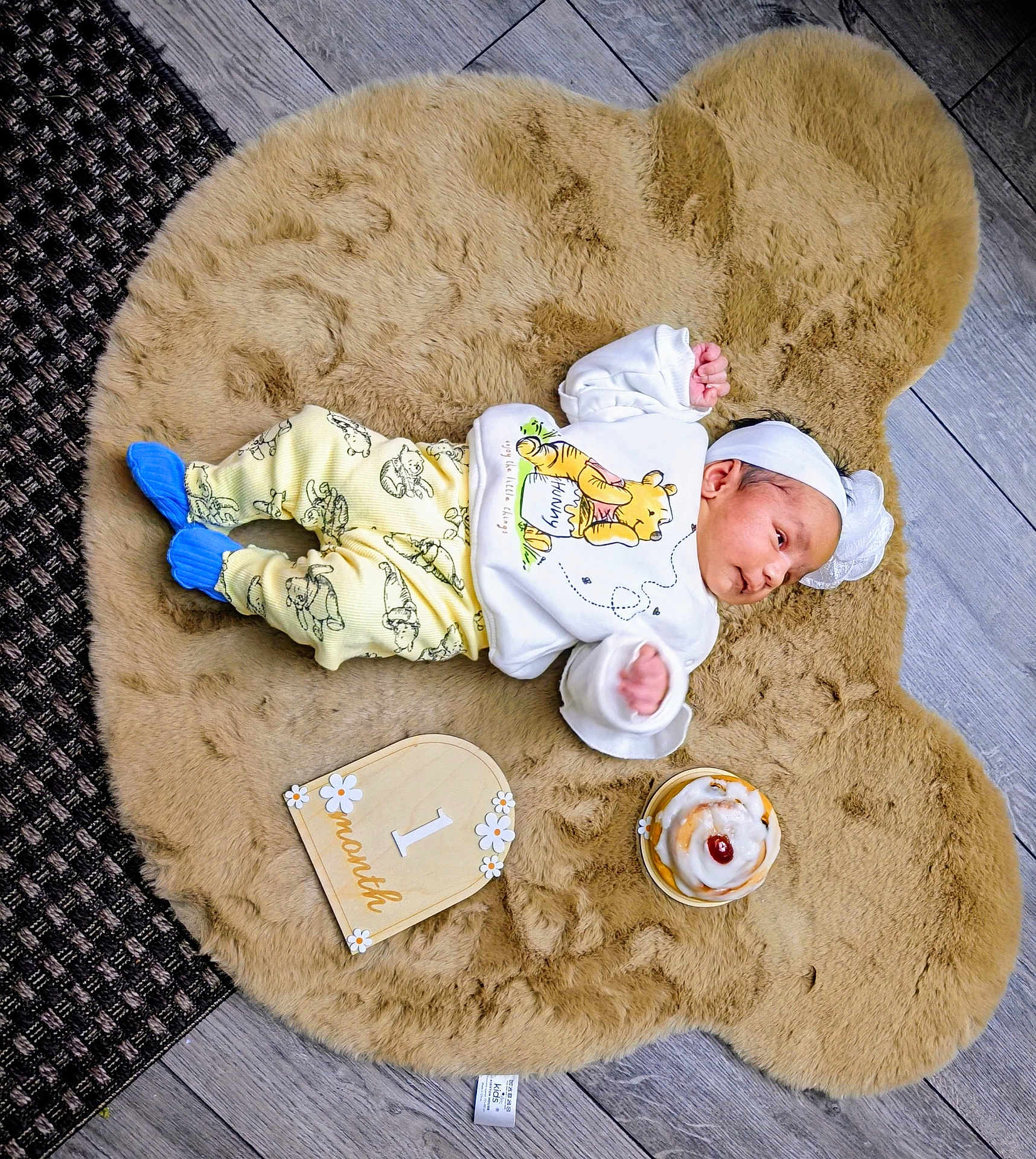Durvi joined the competition — help win amazing prizes! baby, infant, baby_clothes, winnie_the_pooh, blue_socks, fluffy_rug, bear_shaped_rug, wood_floor, cake, milestone_sign, one_month, headband, cute, lying_down, indoors, newborn, small_cake, celebration, portrait, child