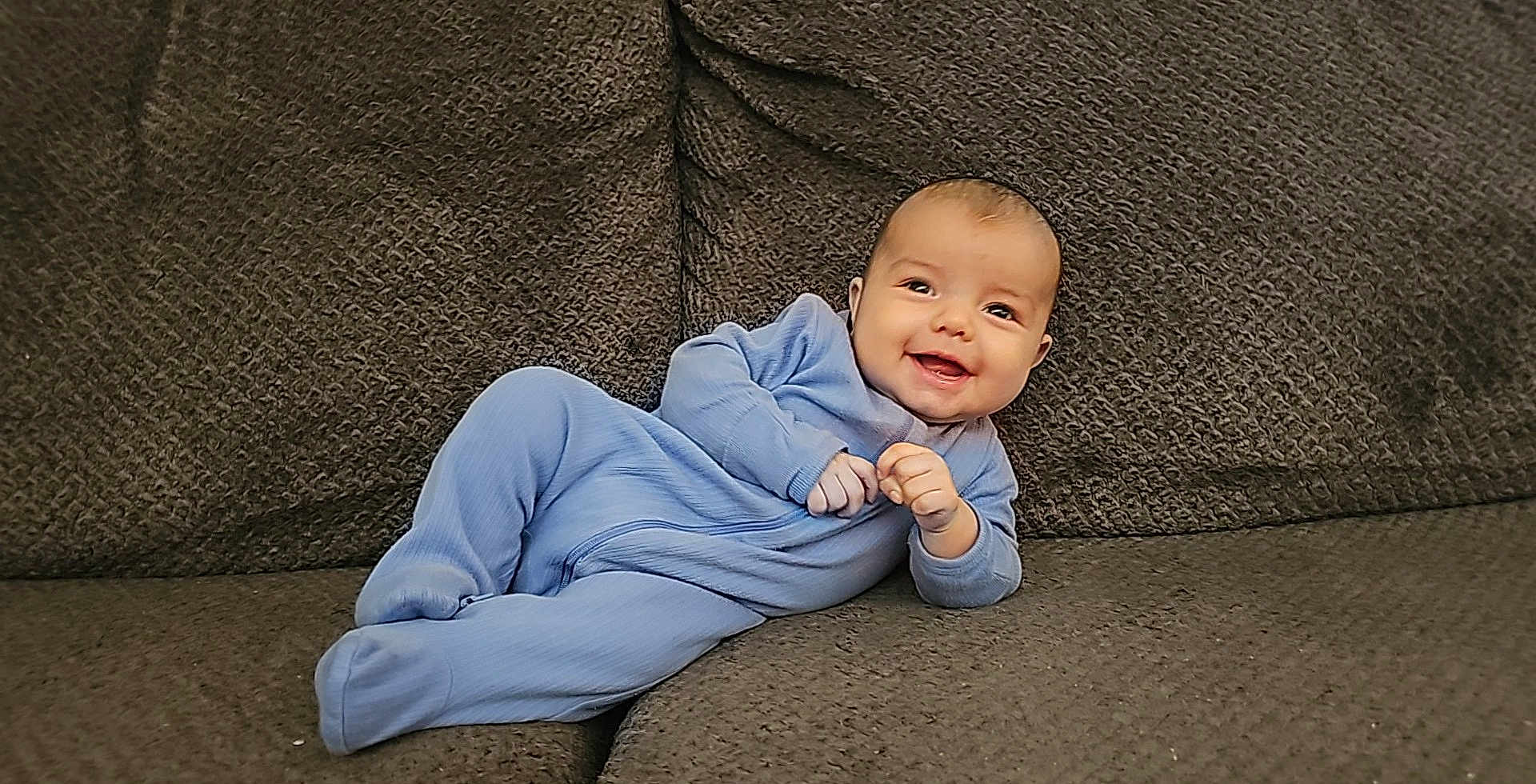 Israel joined the competition — help win amazing prizes! baby, smiling, blue_onesie, couch, textured_fabric, infant, happy, portrait, indoors, relaxed, child, cute, comfort, small_hands, face, young_child, sitting, cozy, casual, home