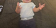 Israel joined the competition — help win amazing prizes! baby, child, smile, couch, clothing, white_shirt, dark_pants, barefoot, indoors, furniture, height_ruler, wooden_door, home, person, happy, standing, texture, cute, infant, expression
