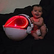 Israel joined the competition — help win amazing prizes! baby, child, diaper, smiling, helmet, red_light, glowing, futuristic, couch, dark_background, indoor, sitting, happy, toy, technology, face, person, infant, home, play