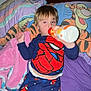 child, pajamas, spiderman, bottle, bed, pillow, tigger, blanket, indoor, sleepwear, relaxed, lying_down, cartoon, bedroom, sleepy, toy, comfort, person, kid, nap