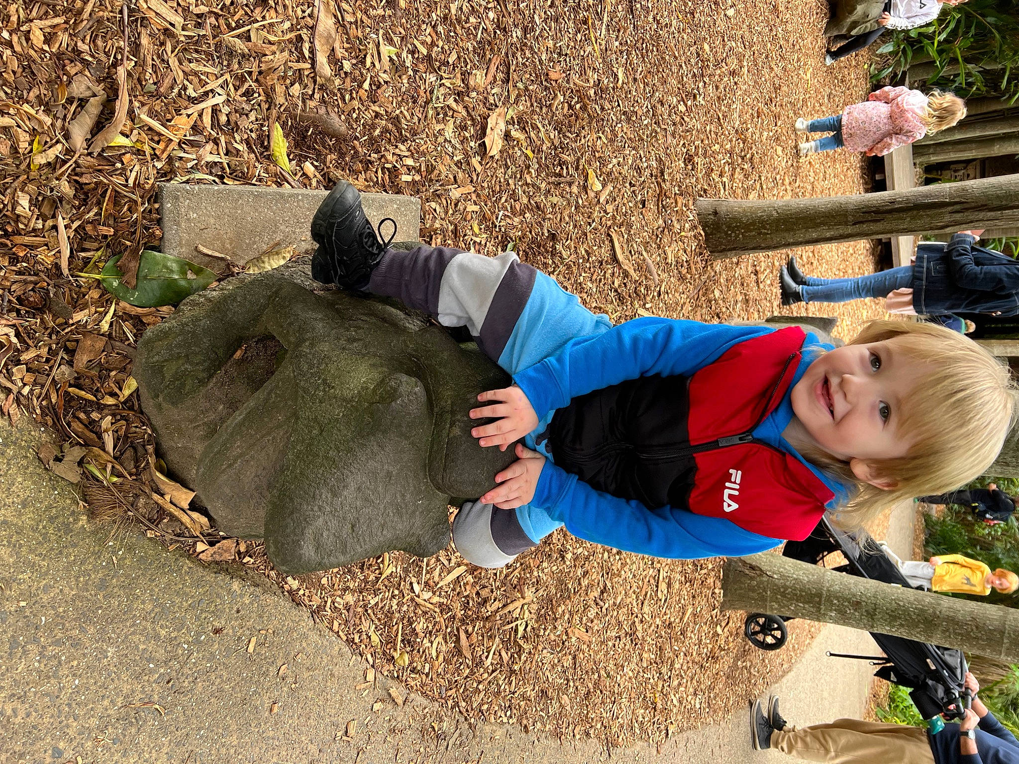 Sebastian is registered to the contest to win money with this photo: baby_toddler_clothing, blurred, child, city, electric_blue, fun, grass, happy, hat, joy, landscape, leaf, leisure, people_in_nature, person, play, recreation, shadow, sitting, smile