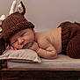 baby, newborn, sleeping, knitted_hat, knitted_pants, antlers, wooden_bed, pillow, cozy, cute, infant, sleep, portrait, indoors, soft_lighting, baby_clothing, child, rest, adorable, peaceful
