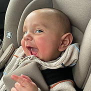 Omar joined the competition — help win amazing prizes! baby, car_seat, child, smile, happy, knitted_sweater, infant, seatbelt, pointing, closeup, indoors, child_seat, cute, person, head, face, apparel, warm_clothing, baby_hand, expression