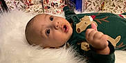 Omar is registered to the contest to win money with this photo: baby, infant, pajamas, reindeer, holiday, wrapping_paper, gift, blue_tin, fluffy_surface, cute, indoors, lying_down, wide_eyes, festive, child, christmas, soft_texture, holiday_decor, person, portrait