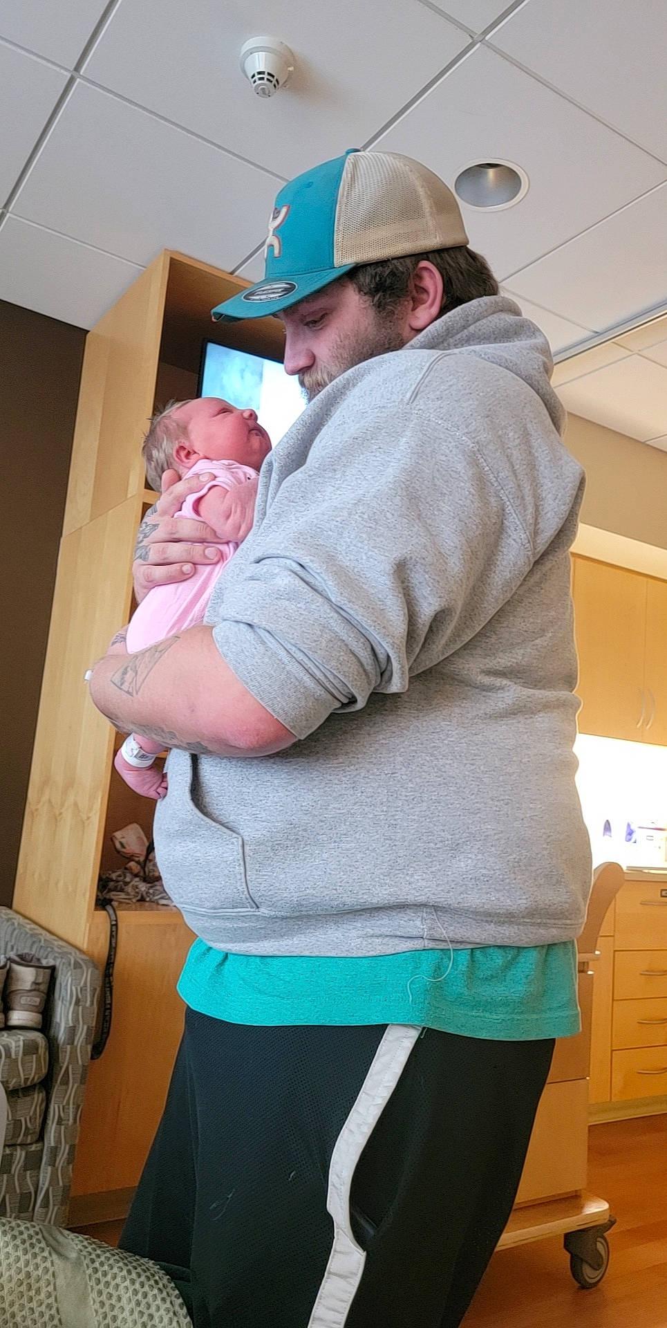 Arizona is registered to the contest to win money with this photo: abdomen, baby, baseball_cap, belt, cabinetry, cap, child, elbow, electric_blue, headwear, joint, magenta, person, room, shoulder, sitting, sleeve, t_shirt, toddler, waist