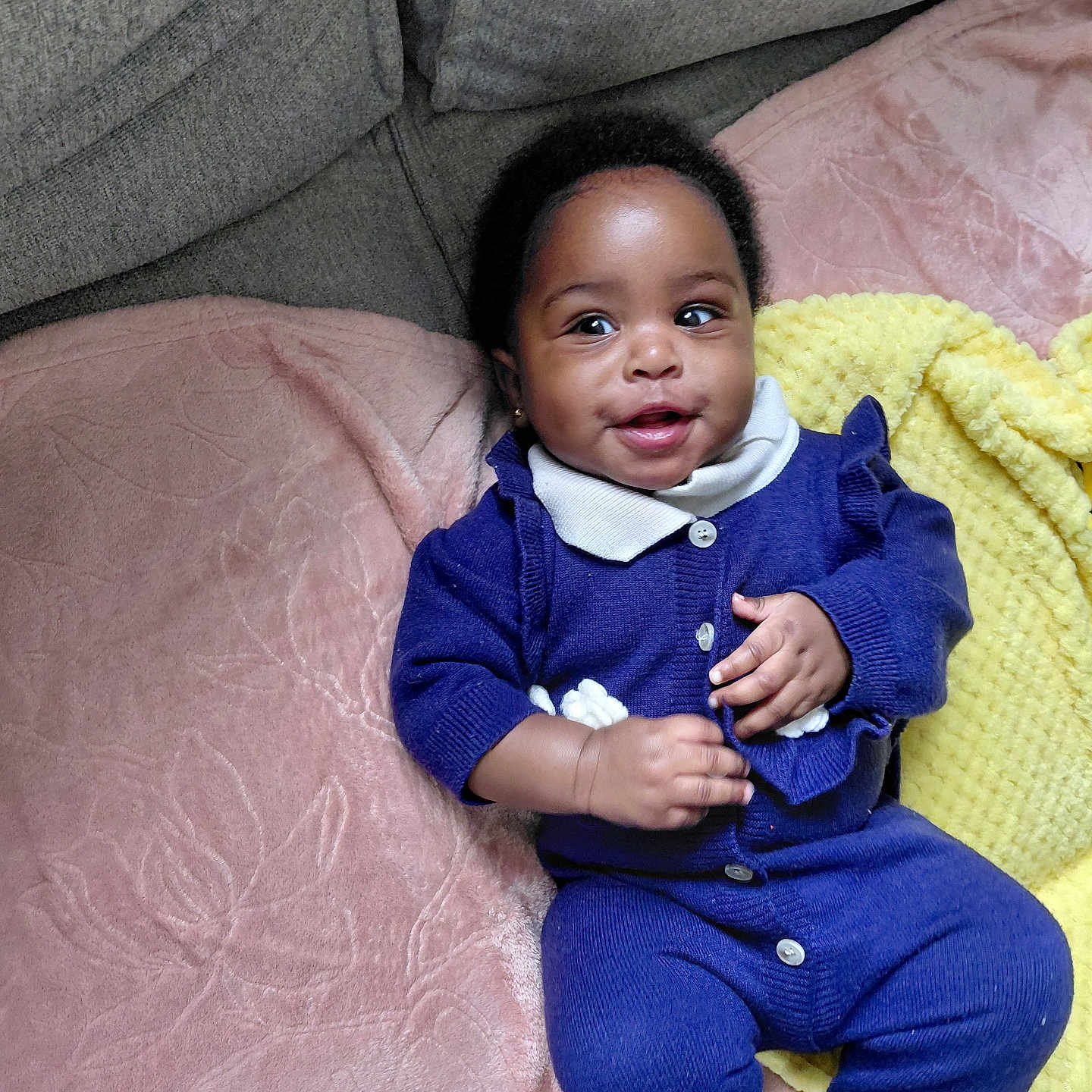 Aindin is registered to the contest to win money with this photo: baby, bodypart, clothing, couch, cushion, face, finger, furniture, hand, happy, head, homedecor, knitwear, pants, person, photography, portrait, sitting, smile, sweater