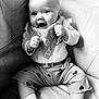 Grace is registered to the contest to win money with this photo: baby, infant, smiling, sitting, couch, bib, clothing, heart_pattern, sock, happy, cute, portrait, child, monochrome, black_and_white, furniture, indoors, person, expression, face
