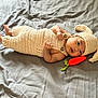 baby, infant, knitted_outfit, bunny_ears, carrot_toy, bed, gray_bedspread, lying_down, cute, soft_texture, handmade, portrait, child, cozy, adorable, newborn, face, headwear, indoor, toy