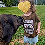 dog, toddler, child, grass, outdoor, shirt, sneakers, tree, sky, greenery, pet, playing, cute, young_child, casual_clothing, animal, nature, daytime, funny_shirt, interaction