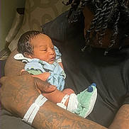 Kymier joined the competition — help win amazing prizes! newborn, baby, adult, tattoo, holding, sleeping, clothing, socks, hospital_bracelet, chair, arm, person, indoors, closeup, love, care, family, portrait, skin, hair