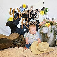 Wrenley joined the competition — help win amazing prizes! baby, cowhide, flowers, cowboy_hat, saddle, blanket, bucket, feathers, decor, blue_eyes, indoor, person, child, rustic, floral_arrangement, jeans, short_sleeve_shirt, name_sign, soft_texture, cute