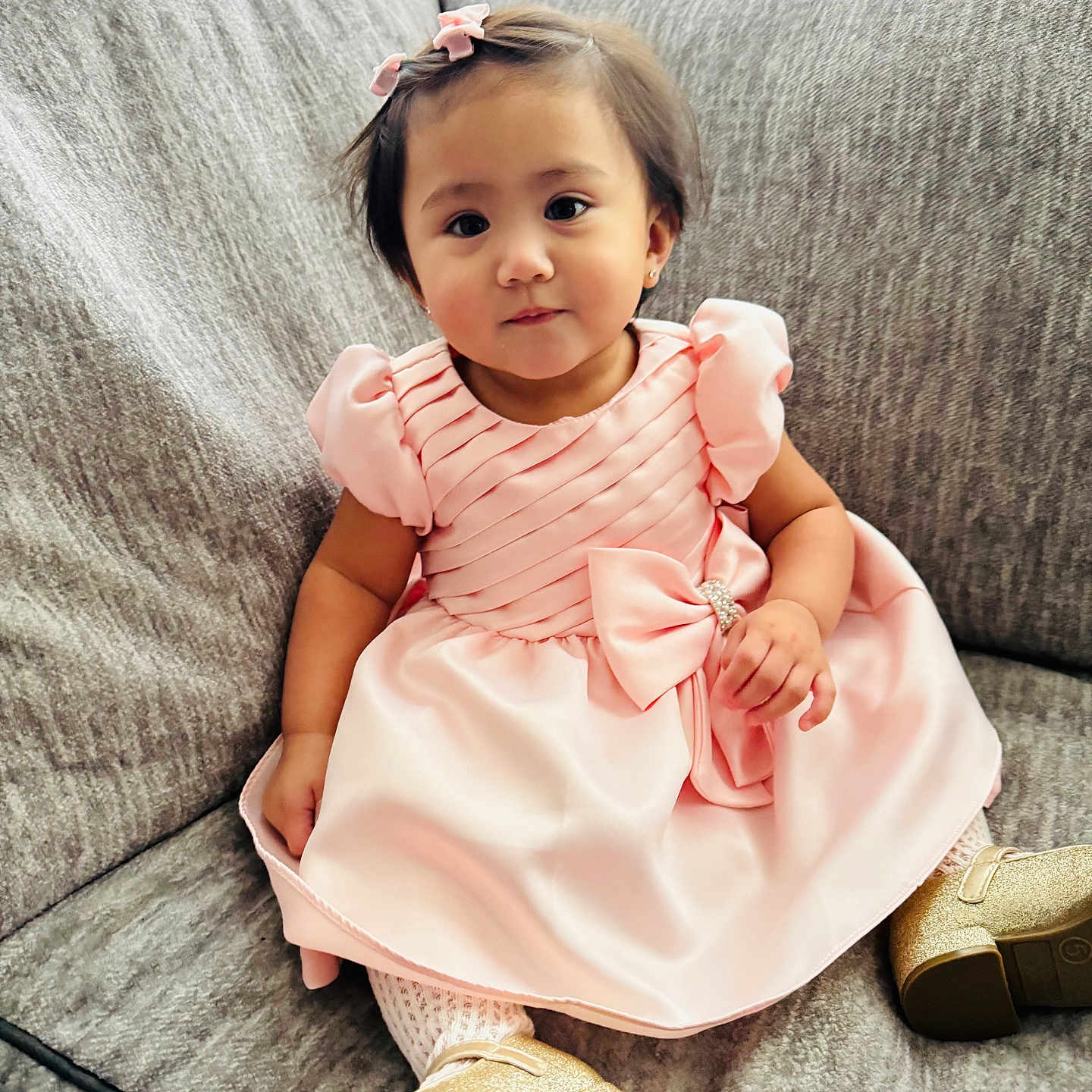Chloe Louise is registered to the contest to win money with this photo: bow, child, couch, cozy, cute, dress, fashion, furniture, gold_shoes, hair_clip, home, indoor, person, pink, portrait, sitting, smiling, sofa, toddler, young_child