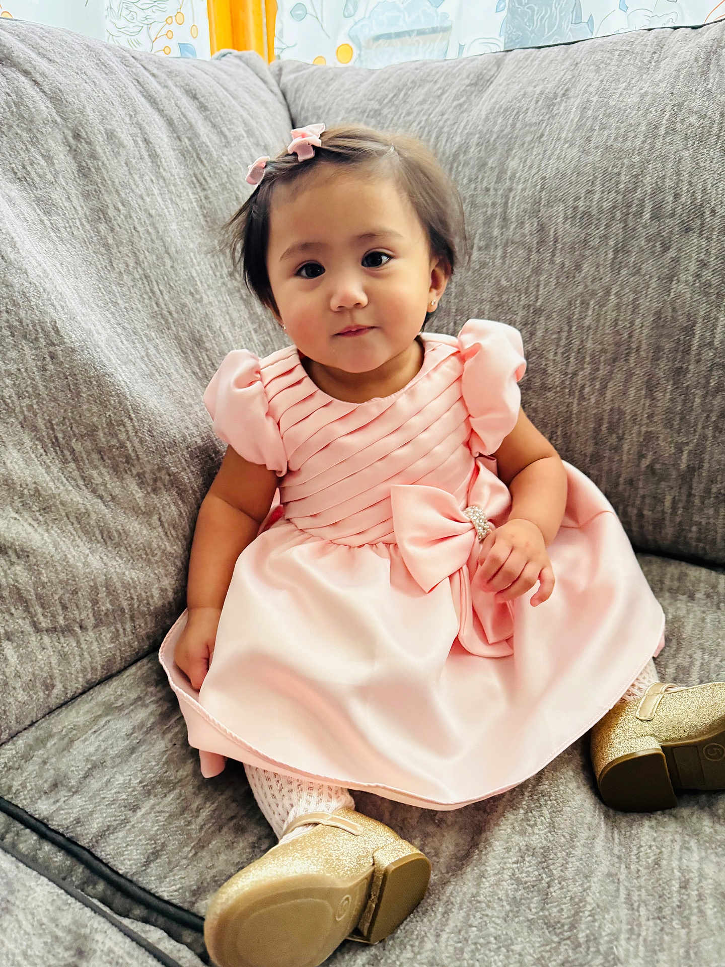 Chloe Louise is registered to the contest to win money with this photo: toddler, child, dress, pink, bow, couch, sofa, gold_shoes, hair_clip, indoor, cute, sitting, young_child, portrait, cozy, smiling, fashion, furniture, person, home