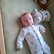 Nolann participe au concours pour gagner de l'argent avec cette photo : baby, bed, calm, child, crib, cute, deer_toy, face, furniture, indoors, infant, onesie, person, plush_toy, portrait, resting, sleepwear, soft_toy, teddy_bear, young_child