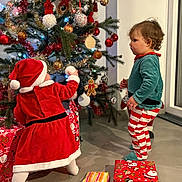 Andría a rejoint le concours — aidez-le/la à gagner de superbes lots ! child, christmas_tree, curiosity, decoration, elf_pants, festive, floor, gift_wrap, gingerbread, green, holiday, indoor, lights, ornaments, play, presents, red, santa_costume, toddler, tree skirt