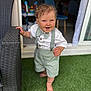 barefoot, bow_tie, child, curly_hair, cute, daylight, door, furniture, grass, happy, home, outdoor, person, portrait, shorts, smiling, suspenders, toddler, white_shirt, wicker_chair