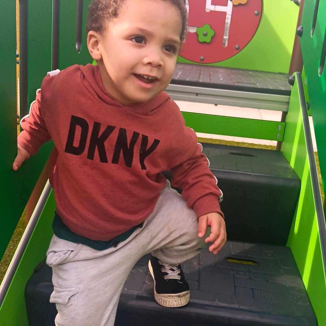 Zyhiere joined the competition — help win amazing prizes! child, playground, steps, smiling, hoodie, red_clothing, green_play_structure, number_four, flowers, sneakers, casual_clothing, outdoor, daylight, happy, active, cute, boy, curly_hair, play, fun