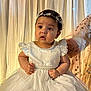 Syra is registered to the contest to win money with this photo: baby, child, dress, white_dress, pearl, headband, balloons, curtain, indoor, portrait, cute, sitting, infant, celebration, decorations, hands, feet, expression, person, soft_light