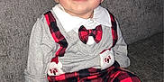 Kieran John is registered to the contest to win money with this photo: baby, child, smiling, plaid, red, black, suspenders, bow_tie, shirt, couch, furniture, footwear, indoors, cute, happy, person, portrait, seated, infant, clothing