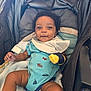 Andrea is registered to the contest to win money with this photo: baby, child, stroller, onesie, bib, blanket, mittens, smiling, infant, cute, happy, portrait, seated, indoors, cozy, clothing, person, face, human, baby_toy