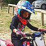 child, helmet, motorcycle, gloves, outdoor, dirt_bike, motorbike, person, vehicle, grass, car, protective_gear, helmet_visor, riding, motor_sport, seated, daylight, safety, youth, park