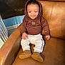 Kevin And Keldrick is registered to the contest to win money with this photo: baby, child, smiling, hoodie, brown_clothing, boots, leather_chair, indoor, happy, seated, person, cute, cozy, infant, casual_wear, home, portrait, small_child, comfortable, fashion