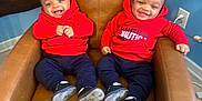 Kevin And Keldrick joined the competition — help win amazing prizes! baby, twins, red_hoodie, navy_pants, black_shoes, smiling, chair, leather_chair, indoor, carpet, wall_outlet, happy, cute, sitting, child, person, two_children, casual_clothing, home, playful