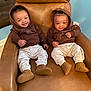 baby, twins, smiling, hoodie, pants, shoes, chair, leather, indoor, cute, infant, child, matching_outfits, happy, sitting, portrait, person, cozy, home, relaxed