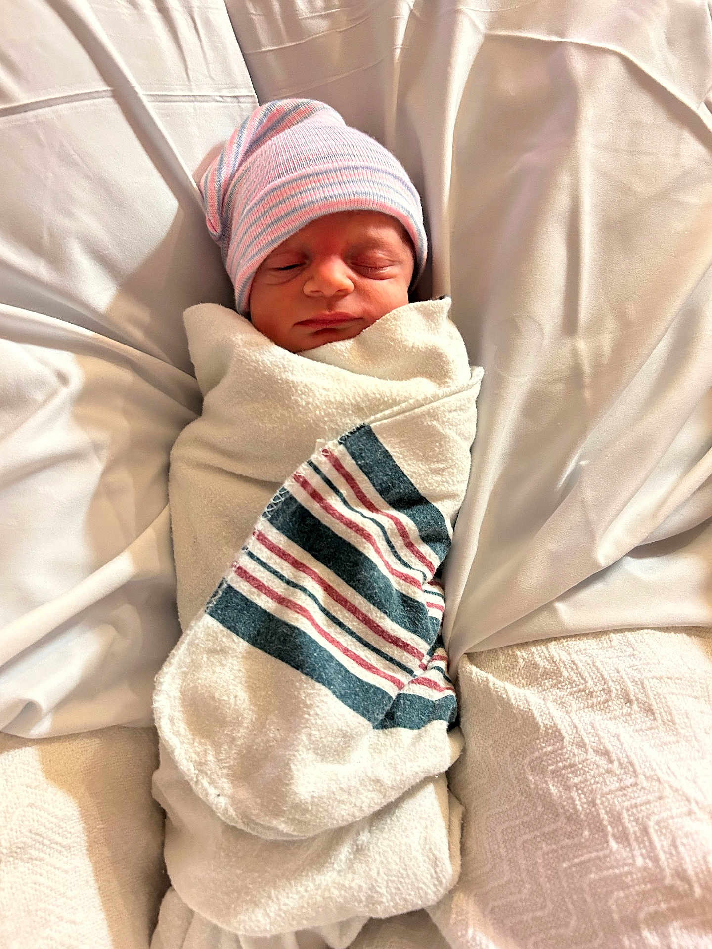 Julian is registered to the contest to win money with this photo: newborn, baby, sleeping, wrapped, blanket, hat, beanie, striped, hospital, bed, white, soft, peaceful, infant, cute, portrait, child, resting, cozy, swaddled