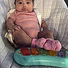 Eliana joined the competition — help win amazing prizes! baby, infant, child, portrait, sitting, high_chair, baby_seat, harness, pink_outfit, polka_dots, socks, musical_toy, toy_keyboard, wide_eyes, indoors, furniture, cushioned_seat, warning_label, soothing_vibration, cute