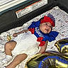baby, infant, child, smiling, lying_down, portrait, patriotic, blue_outfit, red_bow, white_dress, headband, pacifier, socks, play_mat, floral_pattern, balloons, birthday, indoor, nursery, celebration