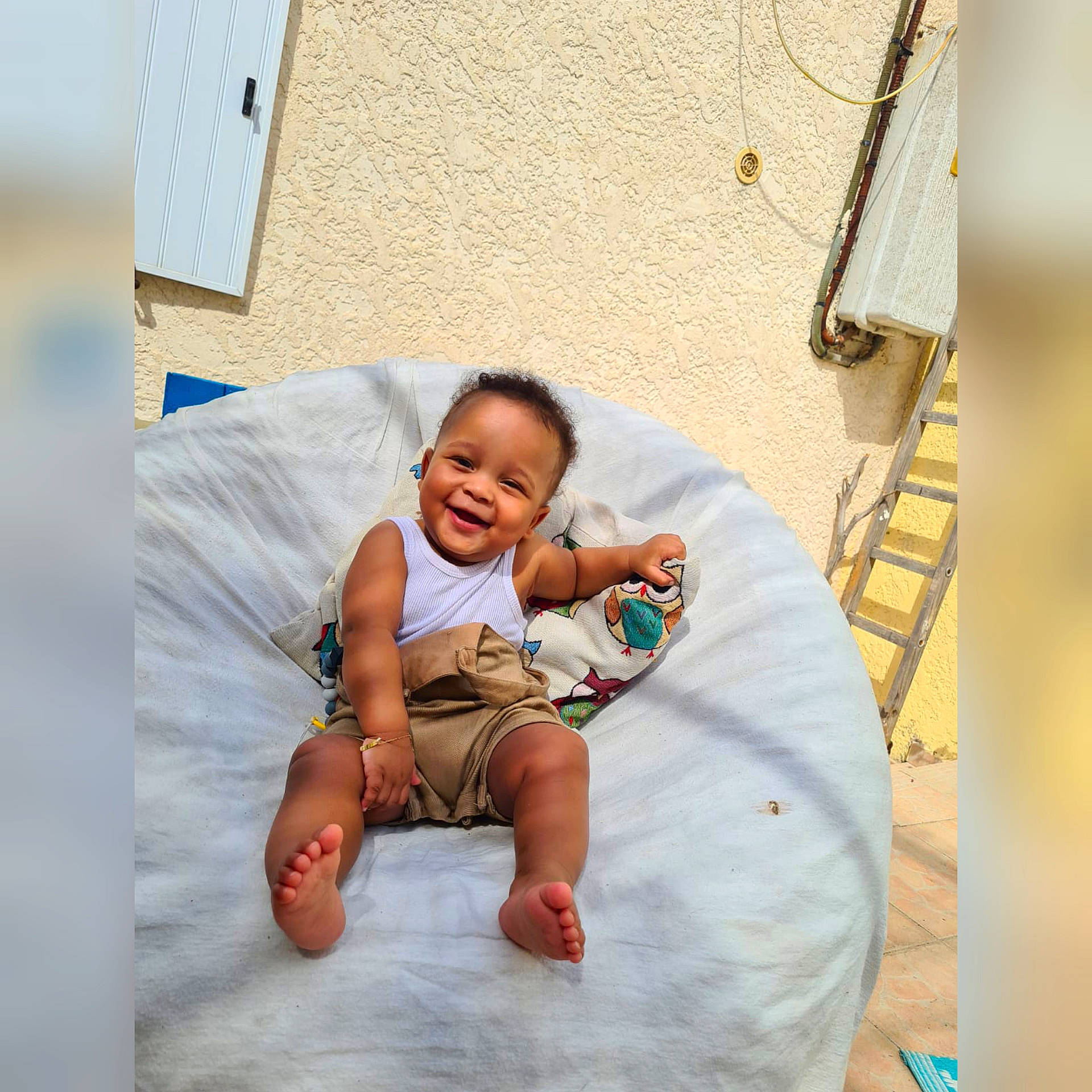 Assad participe au concours pour gagner de l'argent avec cette photo : art, baby, baby_toddler_clothing, barefoot, child, comfort, flooring, foot, fun, happy, joy, leg, leisure, linens, person, room, sitting, smile, t_shirt, textile