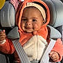 Ava a rejoint le concours — aidez-le/la à gagner de superbes lots ! baby, child, infant, car_seat, safety_harness, hooded_onesie, orange_onesie, headband, smile, cheeks, hand, plush_texture, blanket, seat, portrait, bright_lighting, cute, apparel, eyes, transportation