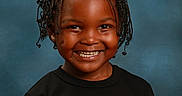 Nycere joined the competition — help win amazing prizes! child, portrait, smiling, happy, studio, blue_background, braided_hair, black_shirt, graphic_t_shirt, standing, frontal_view, face, head, shoulders, indoors, photography, fashion, cheerful, close_up, person