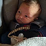 newborn, baby, car_seat, blanket, pacifier, infant, face, child, sitting, child_seat, clothing, indoors, cute, portrait, resting, young_child, baby_boy, soft_lighting, warm, comfort
