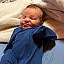 Camille joined the competition — help win amazing prizes! baby, infant, blue_onesie, blanket, tongue_out, cute, lying_down, soft_texture, sleepwear, child, newborn, cozy, smiling, face, head, skin, person, bed, comfort, resting