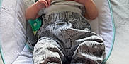 Camille is registered to the contest to win money with this photo: baby, infant, baby_rocker, clothing, feet, hand, face, toy, cushion, pattern, indoor, person, wood_floor, fabric, comfort, cute, resting, child, newborn, soft