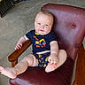 baby, child, infant, sitting, chair, maroon, leather, clothing, blue_eyes, playful, indoor, concrete_floor, tool, wooden_armrest, cute, smile, person, shorts, tshirt, casual