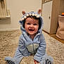 baby, child, smiling, blue_onesie, costume, monster_costume, ears, teeth, carpet, floor, indoor, cute, happy, infant, sitting, clothing, person, portrait, room, furniture