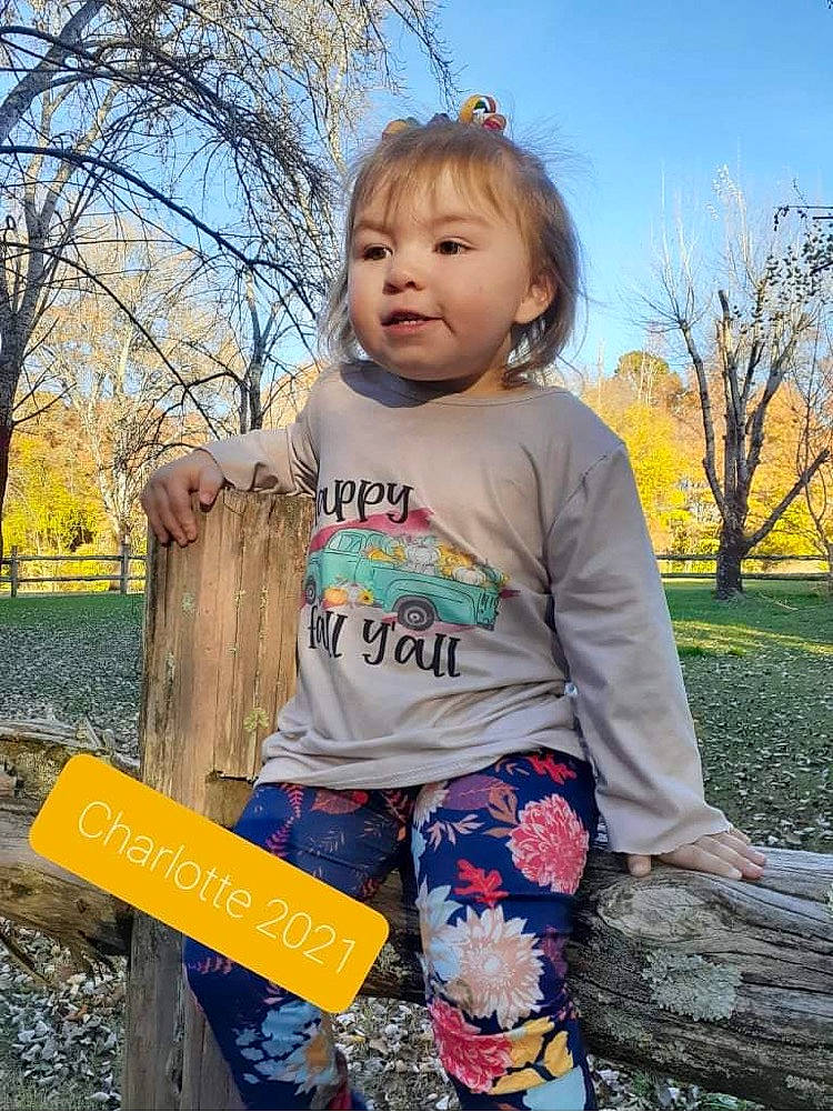 Charlotte Grace is registered to the contest to win money with this photo: baby_toddler_clothing, blond, facial_expression, fun, grass, hairstyle, happy, leisure, people_in_nature, person, plant, public_space, recreation, sky, sleeve, standing, t_shirt, toddler, tree, wood