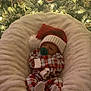 baby, infant, pacifier, santa_hat, plaid_pajamas, christmas_tree, ornaments, lights, cushion, blanket, holiday, festive, cozy, sleeping, indoor, decorations, celebration, warm_lighting, cute, child