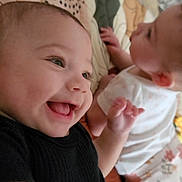 Peyton is registered to the contest to win money with this photo: baby, infant, smiling, joyful, black_clothing, floral_pajamas, blanket, cozy, cute, happy, child, lying_down, face, head, hand, skin, two_babies, indoors, soft, playful