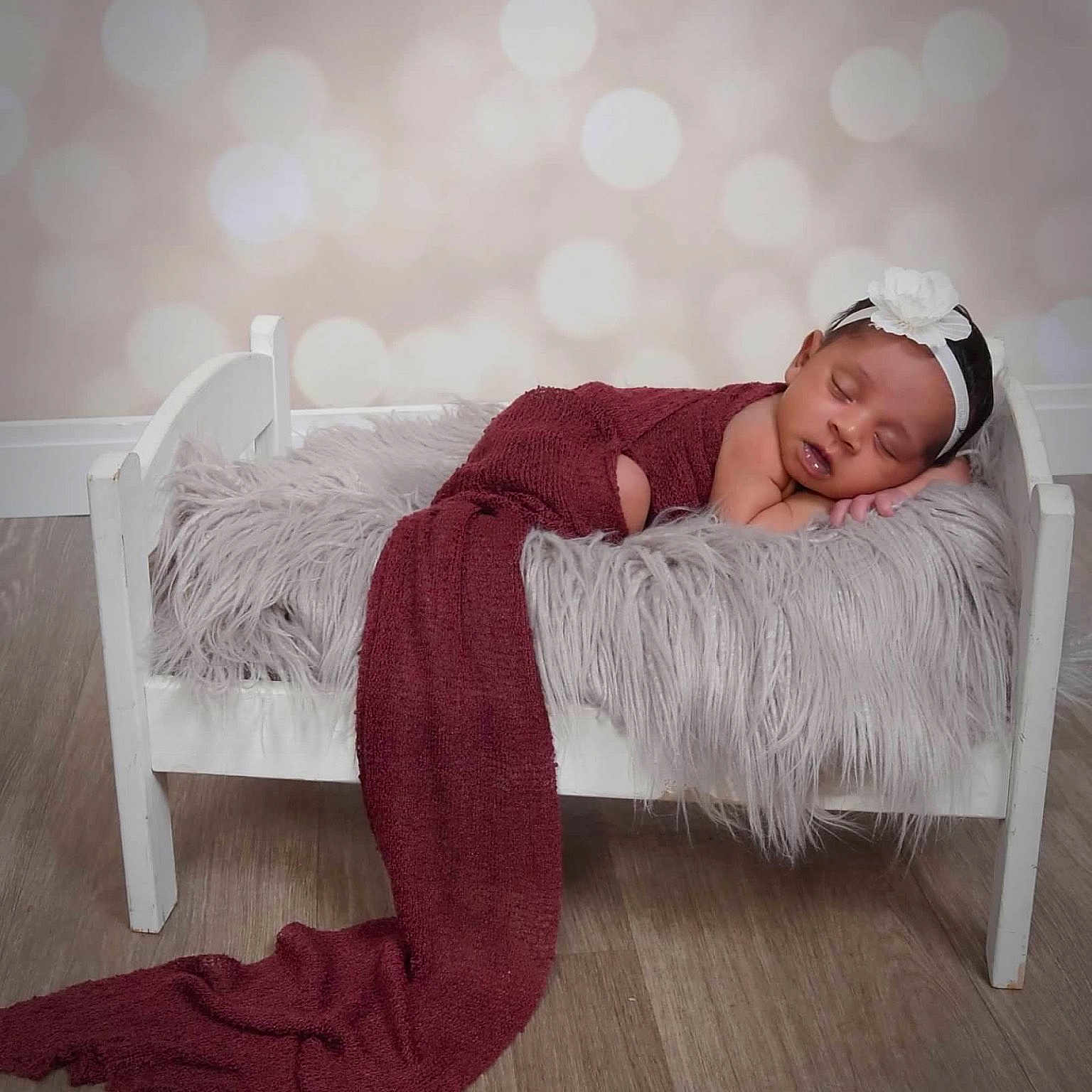 Annalee joined the competition — help win amazing prizes! baby, bed, blanket, child, cozy, cute, decor, flower, fur_texture, headband, indoor, infant, maroon_cloth, peaceful, portrait, resting, sleeping, soft_light, white_bed, wood_floor